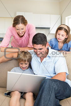 Family using laptop in living room