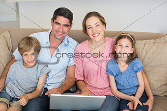 Parents and children with laptop on sofa