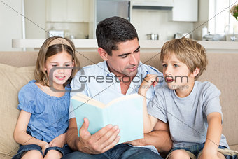 Father teaching children on sofa