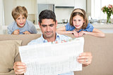 Father and children reading newspaper
