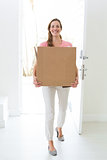 Woman carrying cardboard box in new house