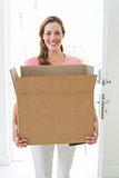 Woman carrying cardboard box in house