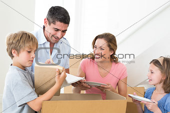 Family unpacking cardboard box in house