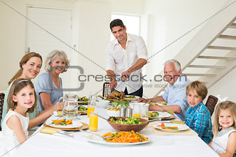 Smiling father serving meal to family