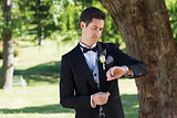 Attractive groom checking time in garden