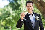 Smiling groom holding champagne flute in garden
