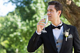 Thoughtful groom drinking champagne