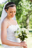 Shy bride holding flower bouquet in garden