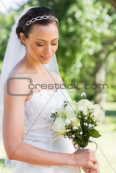 Shy bride holding flower bouquet in garden