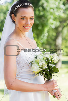 Confident bride holding flower bouquet in garden