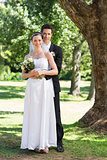 Groom and bride with flower bouquet in park