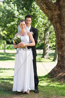 Groom and bride with flower bouquet in park