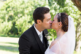 Bride and groom kissing each other in garden