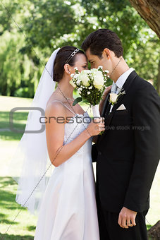 Loving couple kissing behind bouquet in garden