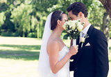 Couple kissing behind bouquet in garden