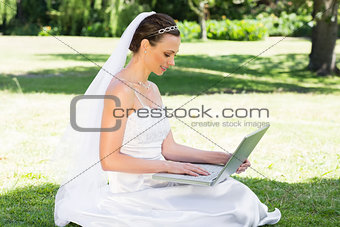 Attractive bride using laptop in garden