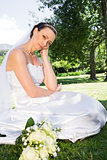 Sad bride with hand on chin in garden