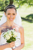 Bride smiling while holding flower in garden