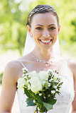 Happy young bride with flowers in garden
