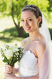 Young bride holding bouquet in garden