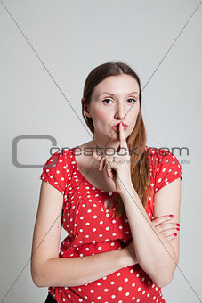 Attractive woman with finger over pursed lips