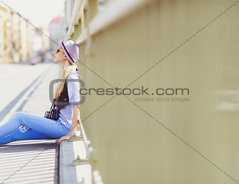 Young hipster sitting on city street