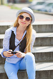 Portrait of young hipster sitting on bench in the city