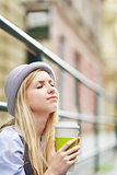 Young hipster enjoying cup of hot beverage in the city