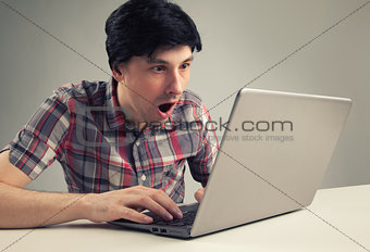 shocking man reading message on laptop computer