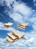 Three open books flying on blue sky
