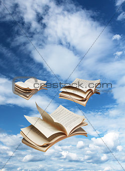 Three open books flying on blue sky