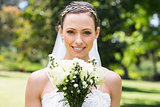Bride with flower bouquet smiling in garden