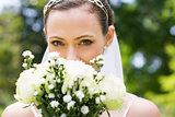 Bride peeking over bouquet in garden