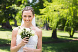 Attractive bride holding flower bouquet in garden