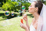 Beautiful bride blowing bubbles in garden