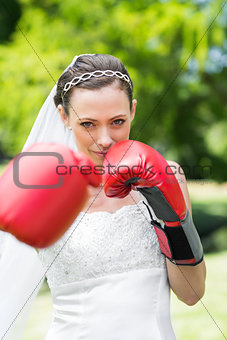 Bride with boxing gloves punching in garden