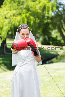 Bride with boxing gloves punching in park