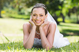 Bride in wedding gown lying on grass