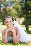 Beautiful bride lying on grass in park