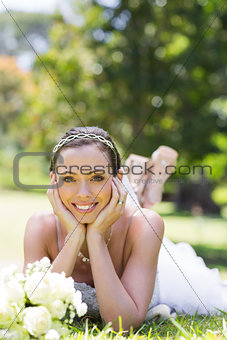 Bride relaxing on grass in the park