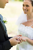 Young groom placing ring on brides finger