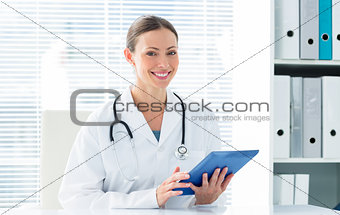 Happy female doctor holding digital tablet