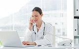 Doctor using land line phone and laptop