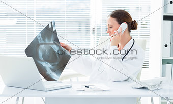 Doctor using telephone while studying Xray