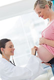 Doctor examining stomach of pregnant woman