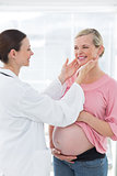 Doctor examining thyroid glands of pregnant woman