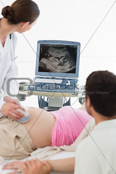 Doctor performing ultrasound on expectant woman