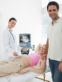 Expectant couple with doctor performing ultrasound