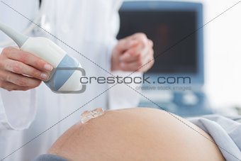 Doctor applying gel on belly of pregnant woman