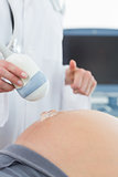 Doctor using ultrasound on belly of pregnant woman
